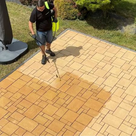 Professional spraying a protective treatment evenly across an outdoor stone surface